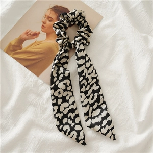 Detail of white and black leopard print satin hair scrunchie with long ribbons on linen
