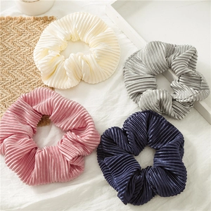 Close-up of four pleated satin hair scrunchies in cream, gray, pink and navy blue silk fabric
