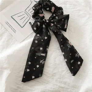 Détail d'un chouchou en mousseline fleurie avec long ruban sur fond de tissu blanc