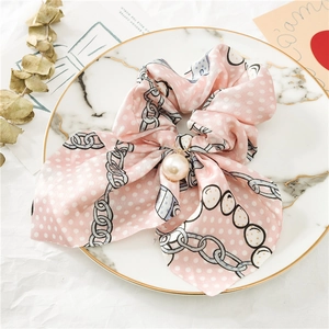 Vue détaillée du chouchou en satin rose à pois blancs et élégante perle en pendentif