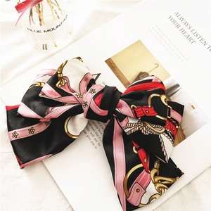 Detail of satin bow hair clip with vintage chain and floral print in chic magazine style