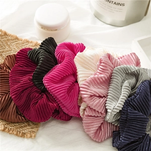 Assorted pleated satin hair scrunchies in various colors stacked on a soft background