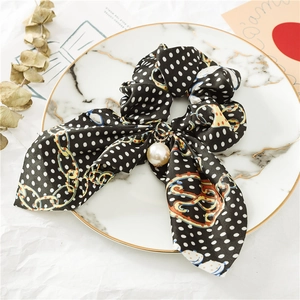 Détail du chouchou en satin noir à pois avec longs rubans et breloque en perle