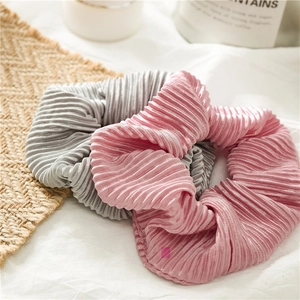 Close-up of pink and silver pleated satin scrunchies with elegant glossy texture