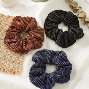 Close-up of pleated satin hair scrunchies in brown, black, and navy blue fabric