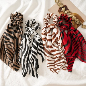 Detailed flat lay of zebra print scrunchies with long ribbons on white fabric