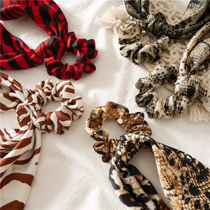 Leopard and snake print hair scrunchies with long ribbons on white textured fabric