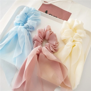 Detailed close-up of light blue, pink and beige chiffon scrunchies with long ribbons