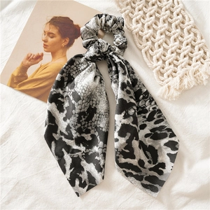 Close-up of black and white animal print hair scrunchie with long ribbons on knit fabric