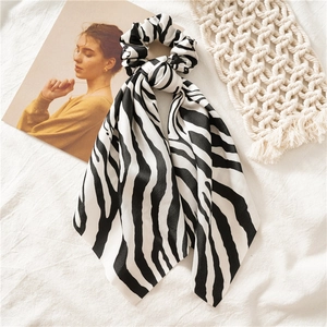 Close-up of zebra pattern scrunchie with long ribbons on white textured linen background
