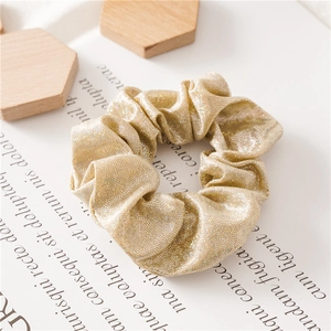 Macro-opname van champagnegouden glitter scrunchie met glinsterende metalen deeltjes