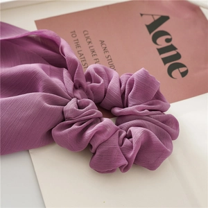 Macro detail of purple chiffon hair scrunchie with long ribbon and soft fabric texture
