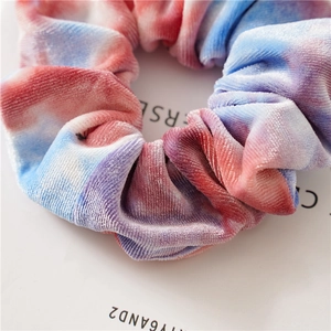 Close-up of tie-dye velvet scrunchie showing soft plush texture and elastic hair tie detail