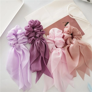 Detail of four pastel chiffon bow hair scrunchies with long ribbons on a white background