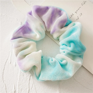 Detailed view of tie-dye velvet hair scrunchie with purple and blue gradient texture