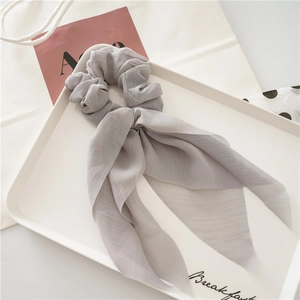 Detail of light gray chiffon hair scrunchie with long ribbons on white tray
