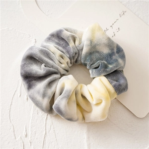 Detailed view of tie-dye velvet scrunchie with soft grey-blue and yellow striped texture