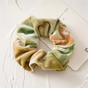 Detailed view of the soft velvet tie-dye scrunchie featuring green and yellow textures