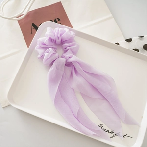 Detail of lavender chiffon scrunchie with long ribbon bow on elegant white tray