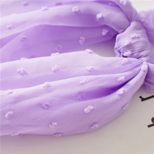 Detailed macro view of light purple Swiss dot seersucker fabric texture for hair accessories