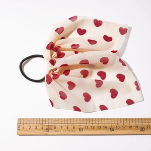 Gros nœud pour cheveux beige à motifs cœurs rouges sur un chouchou de 17 cm de long