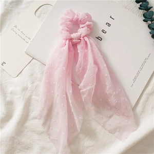 Close-up of pink seersucker scrunchie with jacquard dots and long elegant ribbons