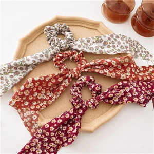 Detailed view of floral scrunchies with long ribbons in ivory, orange, and wine red