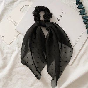 Detail of black polka dot mesh scrunchie with long scarf ribbons on a soft background