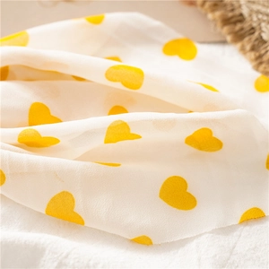 Détail du tissu en mousseline crème avec des motifs en forme de cœur jaune vif