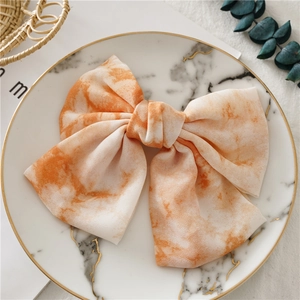 Détail d'un grand nœud papillon à teinture tie-dye orange sur un plateau en marbre élégant