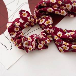Macro detail of wine red floral scrunchie with daisy patterns and ribbed fabric texture