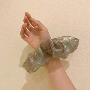 Close-up of bronze organza scrunchie with iridescent metallic luster worn on a wrist
