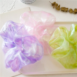 Detailed macro shot of iridescent organza scrunchies in pastel colors with soft shimmer