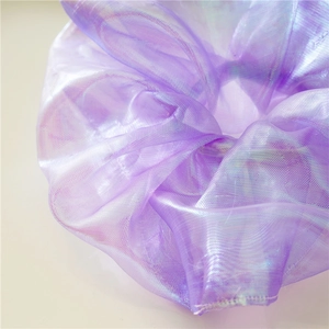 Detailed macro view of pearlescent organza fabric with mermaid glow on purple scrunchie