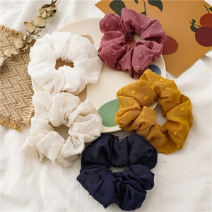 Detailed close-up of five seersucker scrunchies in cream pink and navy with dot texture