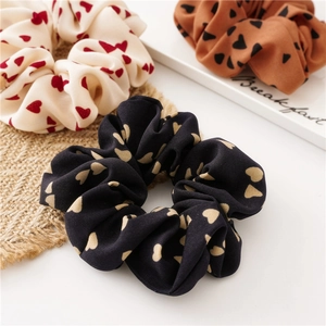 Drei gemusterte Haargummis mit Herz-Print in Creme, Schwarz und Caramel aus Satin