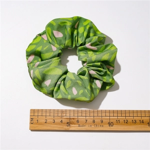 Floral green scrunchie with pink patterns and wooden ruler for 10cm size reference