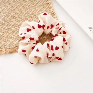 Detail eines cremefarbenen Scrunchies mit roten Herzen und weichem Chiffon-Stoff
