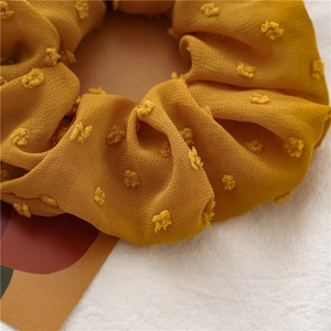 Detailed close-up of ginger yellow seersucker scrunchie with 3D dobby dot texture