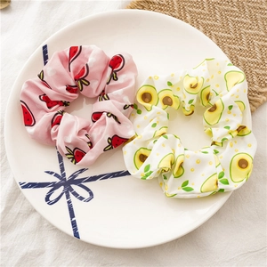 Detailed view of handmade fruit pattern hair scrunchies on a white porcelain dish