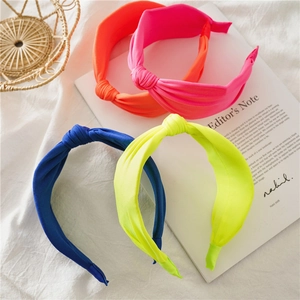 Flat lay of knotted wide headbands in vibrant neon orange, pink, blue and yellow fabric