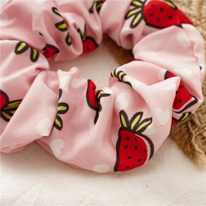 Pink scrunchie with strawberry and heart patterns on natural fabric background