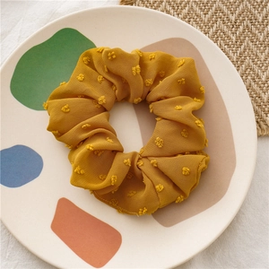 Close-up of ginger yellow seersucker scrunchie with 3D flocking dots on ceramic tray