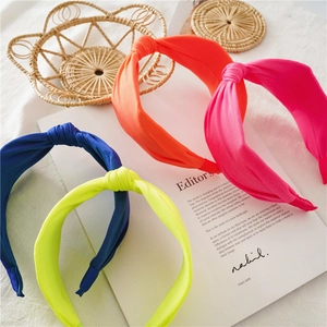 Detail view of colorful knotted fabric headbands in navy, neon yellow, orange and rose pink
