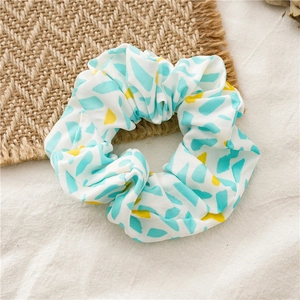 Detail view of a white chiffon oversized scrunchie with blue and yellow abstract prints