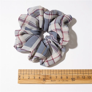 Chouchou à carreaux gris et beige avec règle en bois montrant la taille de dix cm
