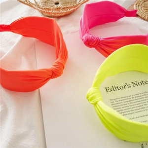 Detailed shot of three neon knotted headbands in vibrant orange, pink and green fabric