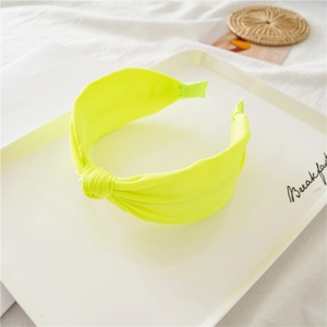 Close-up of bright fluorescent yellow knitted knot headband on a minimalist tray