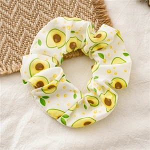 Detailed close-up of avocado print on a soft white chiffon scrunchie with pleated texture