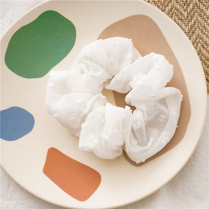 Detail showing white seersucker scrunchie with 3D polka dots on decorative ceramic plate